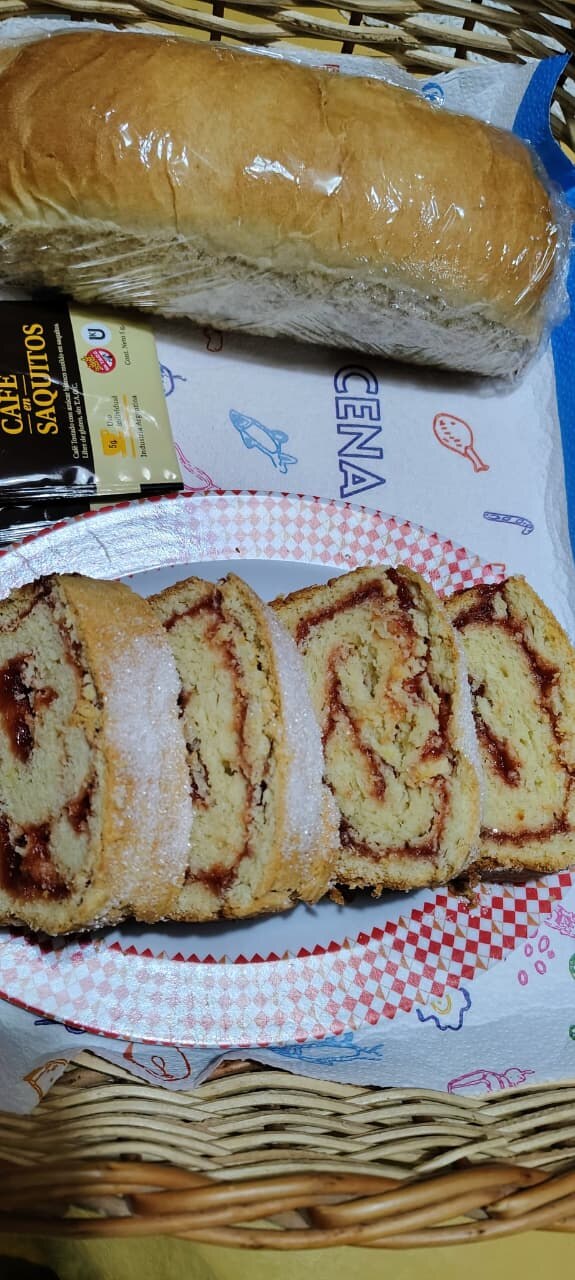 Arrollado de dulce cortado en rodajas, pan casero y café
